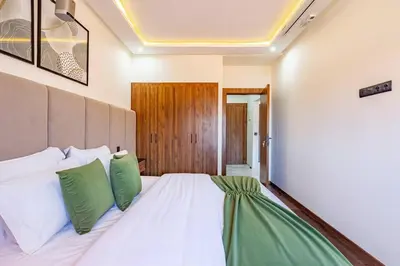 a bedroom with a white bed with green pillows at Luxury Apartment Gueliz, Cinema Bedroom Experience in Marrakech