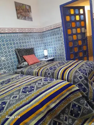 two beds in a room with blue walls at RIAD DAR KADER D in Marrakech
