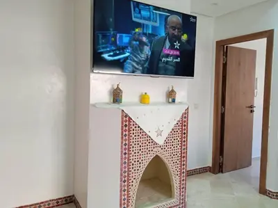 a living room with a table with a tv on the wall at Appart Premium Village Marrakech in Marrakech