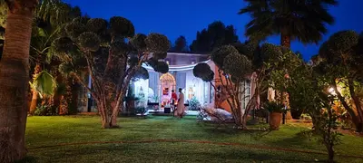 a woman standing outside of a house at night at Marrakech, villa 7 Harmonia, pour 6 personnes avec piscine privée in Marrakech