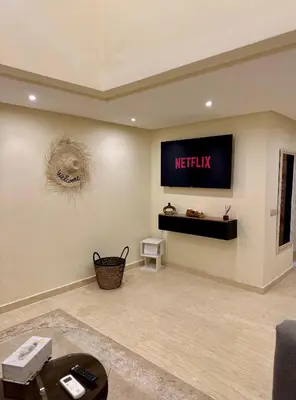 a living room with a nittisk sign on the wall at The Cosy Duplex With Gym Access & Near Mall, Palooza in Marrakech