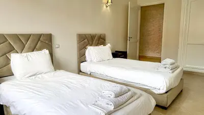 two beds in a room with white sheets and towels at Spacious Apartment 102m2 3 Bedrooms 2 Bathrooms 8 Guests Elevator Self Check in in Marrakech