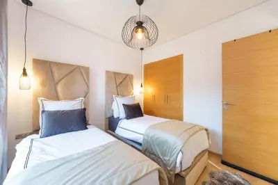 a bedroom with two beds and a chandelier at Appart View Pool - 3 Rooms - Optical Fiber in Marrakech