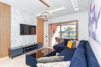 a living room with a blue couch and a tv at Luxueux appartement prestigia golf/vue piscine in Marrakech