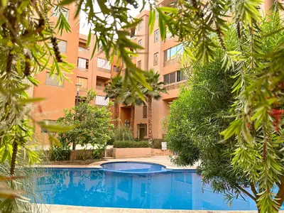 a building with a swimming pool in front of a building at Cozy apartment pool marrakech morocco in Marrakech