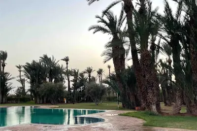 a swimming pool with palm trees in a park at Appart-Oasis/3 Piscines/2 Terrasses in Marrakech