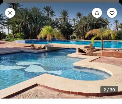 a swimming pool with blue water and palm trees at Appart-Oasis/3 Piscines/2 Terrasses in Marrakech