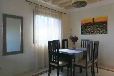 a dining room with a table and chairs and a window at Appart-Oasis/3 Piscines/2 Terrasses in Marrakech