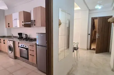 a kitchen with a refrigerator and a stove top oven at Appartement 2 chambres vue Piscine à Guèliz en face la gare de train marrakech in Marrakech
