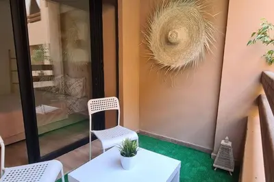 a white chair sitting on a porch with a potted plant at Appartement 2 chambres vue Piscine à Guèliz en face la gare de train marrakech in Marrakech