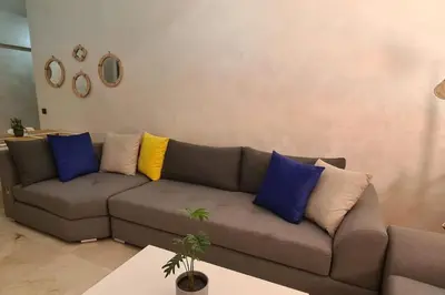a living room with a brown couch with blue and yellow pillows at Appartement 2 chambres vue Piscine à Guèliz en face la gare de train marrakech in Marrakech