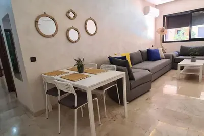 a living room with a table and a couch at Appartement 2 chambres vue Piscine à Guèliz en face la gare de train marrakech in Marrakech