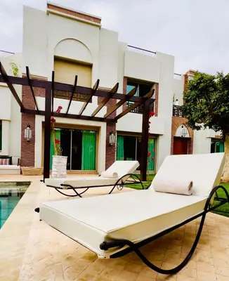 a patio with two beds in front of a house at Villa Jenna in Marrakech