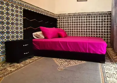 a bedroom with a bed with pink sheets and a wall at Riad Sultana - 10 min à pied de Jemaa El Fna in Marrakech