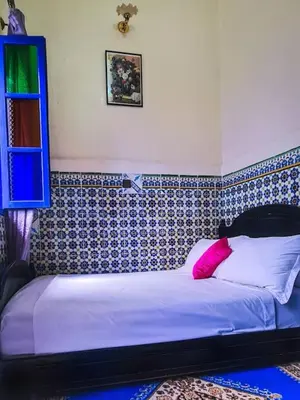 a bedroom with a bed with a pink pillow at Riad Sultana - 10 min à pied de Jemaa El Fna in Marrakech