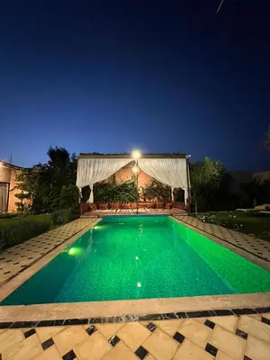 a swimming pool with green water at night at La villa Berbère - Famille uniquement in Marrakech