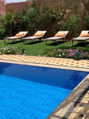 a swimming pool with lounge chairs next to a yard at La villa Berbère - Famille uniquement in Marrakech