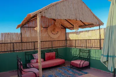 a porch with a couch and two chairs and a umbrella at Appartement MSholidays Gazelle Marrakech in Marrakech