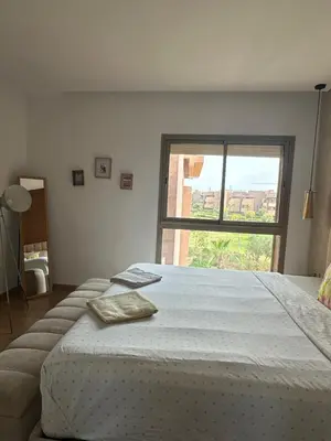 a bedroom with a large bed with a large window at Prestigia Golf Vue Atlas et Piscine in Marrakech