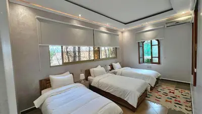 a bedroom with three beds and two windows at Luxurious Villa with private pool, Jacuzzi & Cuisinière in Marrakech