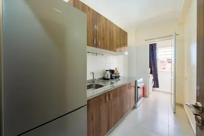 a kitchen with wooden cabinets and a stainless steel refrigerator at Appartement 2 chambres Aéroport in Marrakech