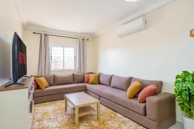 a living room with a couch and a tv at Appartement 2 chambres Aéroport in Marrakech