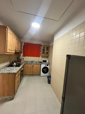 a small kitchen with wooden cabinets and a refrigerator at Appartement piscine in Marrakech