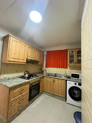a kitchen with wooden cabinets and a sink and a dishwasher at Appartement piscine in Marrakech