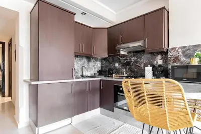 a kitchen with brown cabinets and a rattan chair at C-Appartement de luxe plein centre de gueliz avec piscine parking wifi netflix in Marrakech