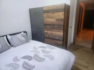 a bedroom with a white bed with a wooden wall at appartement cosy plein centre in Marrakech