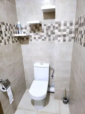 a bathroom with a toilet and a tiled wall at appartement cosy plein centre in Marrakech