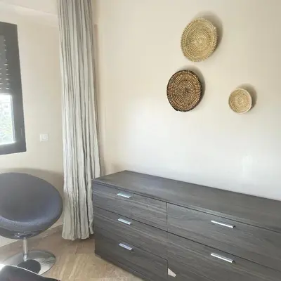 a room with a dresser with a chair and two baskets on the wall at Séjour lumineux confort et design in Marrakech