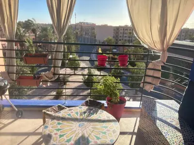 a balcony with potted plants and a table and a window at Séjour lumineux confort et design in Marrakech