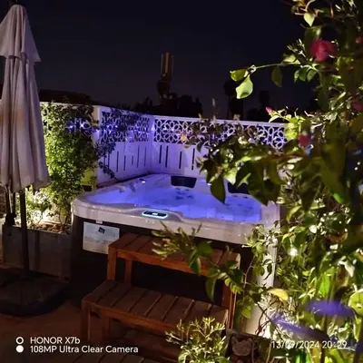 a jacuzzi tub in a backyard at night at RIAD & SPA SOUS LE SOLEIL CHEZ Jérôme & Paméla in Marrakech