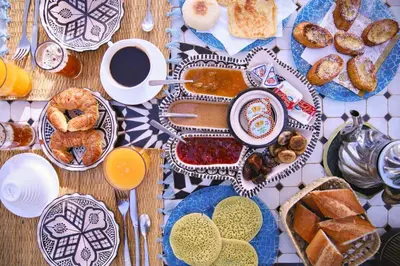 a table topped with plates of food and cups of coffee at RIAD & SPA SOUS LE SOLEIL CHEZ Jérôme & Paméla in Marrakech