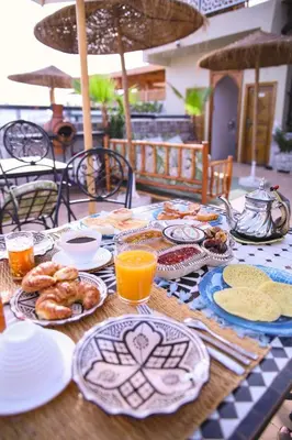 a table topped with plates of food and orange juice at RIAD & SPA SOUS LE SOLEIL CHEZ Jérôme & Paméla in Marrakech