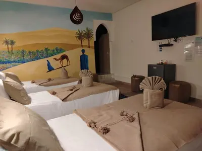 a room with two beds and a tv on the wall at RIAD & SPA SOUS LE SOLEIL CHEZ Jérôme & Paméla in Marrakech
