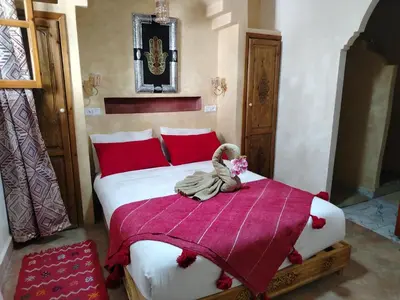 a bedroom with a large bed with red pillows at RIAD & SPA SOUS LE SOLEIL CHEZ Jérôme & Paméla in Marrakech