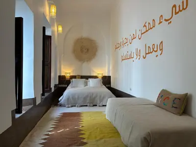 a bedroom with two beds and a writing on the wall at Neroli le Riad, idéalement situé in Marrakech