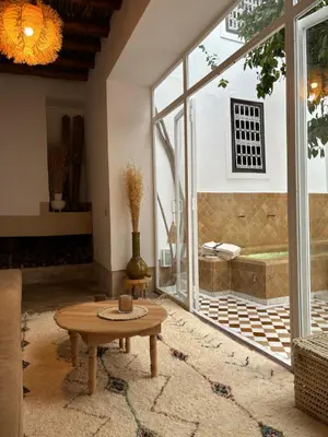 a living room with a table and a large window at Neroli le Riad, idéalement situé in Marrakech