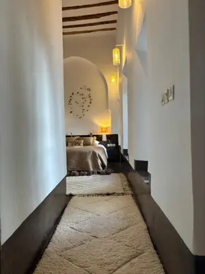 a bedroom with a bed and a white wall at Neroli le Riad, idéalement situé in Marrakech