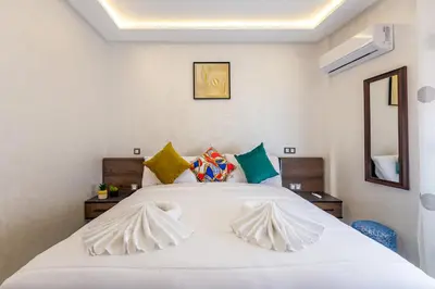 a bedroom with a large white bed with colorful pillows at Vittoria Guest House Marrakech in Marrakech