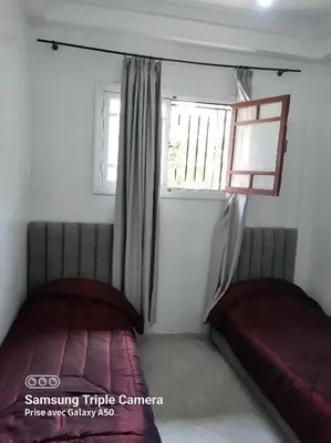 two beds in a small room with a window at إقامة علياء in Marrakech