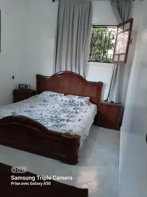 a bedroom with a bed with a wooden frame and a window at إقامة علياء in Marrakech