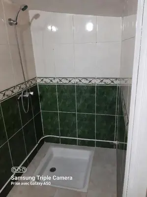 a green tiled shower with a white tub in a bathroom at إقامة علياء in Marrakech