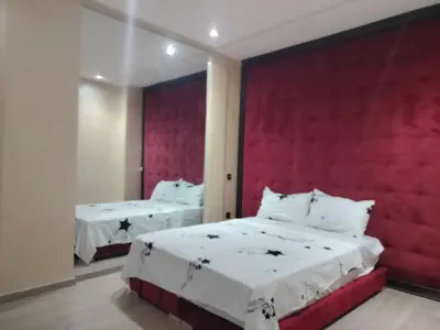 a bedroom with two beds and a red wall at résidence assafa central H26 in Marrakech