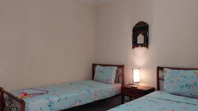 a bedroom with two beds and a table with a lamp at Agréable maison familiale in Marrakech