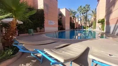 a group of lounge chairs next to a swimming pool at Agréable maison familiale in Marrakech