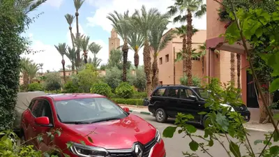 a red car and a black car parked next to a building at Agréable maison familiale in Marrakech