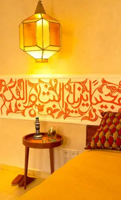 a bedroom with a bed and a table with a lamp at Riad Romeo in Marrakech